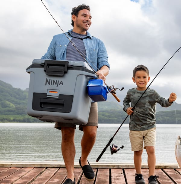 Father and son carrying cooler during fishing trip